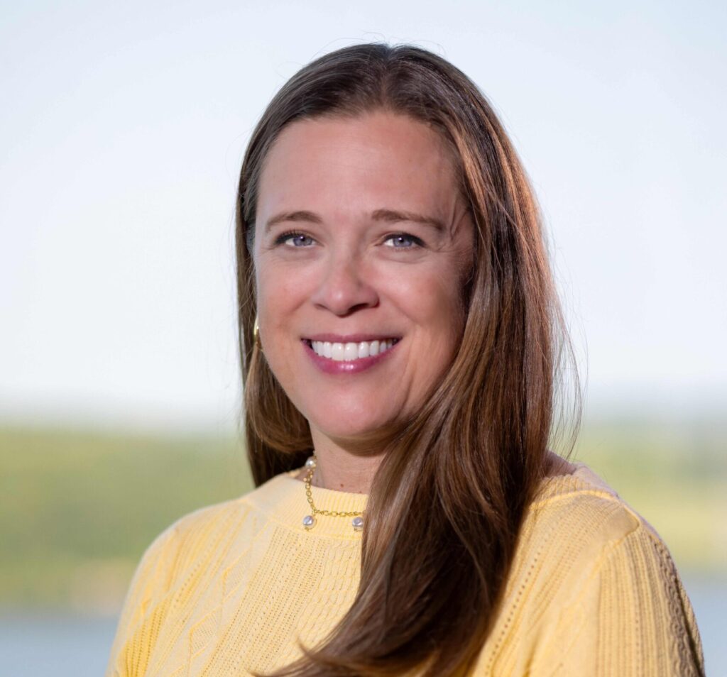 Woman with brown hair and wearing a yellow shirt smiling